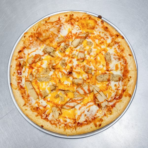 A whole buffalo chicken pizza, topped with white and orange cheese, and chicken pieces.