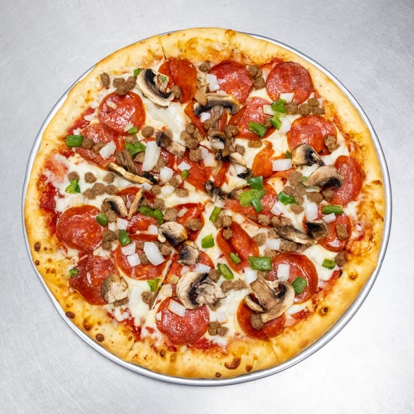 A whole pizza with pepperoni, sausage, mushrooms, green peppers, and onions on a metal tray.