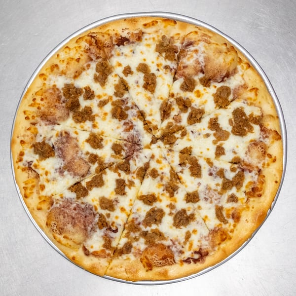 A whole, sliced pizza with white cheese and crumbled sausage on a metal tray.