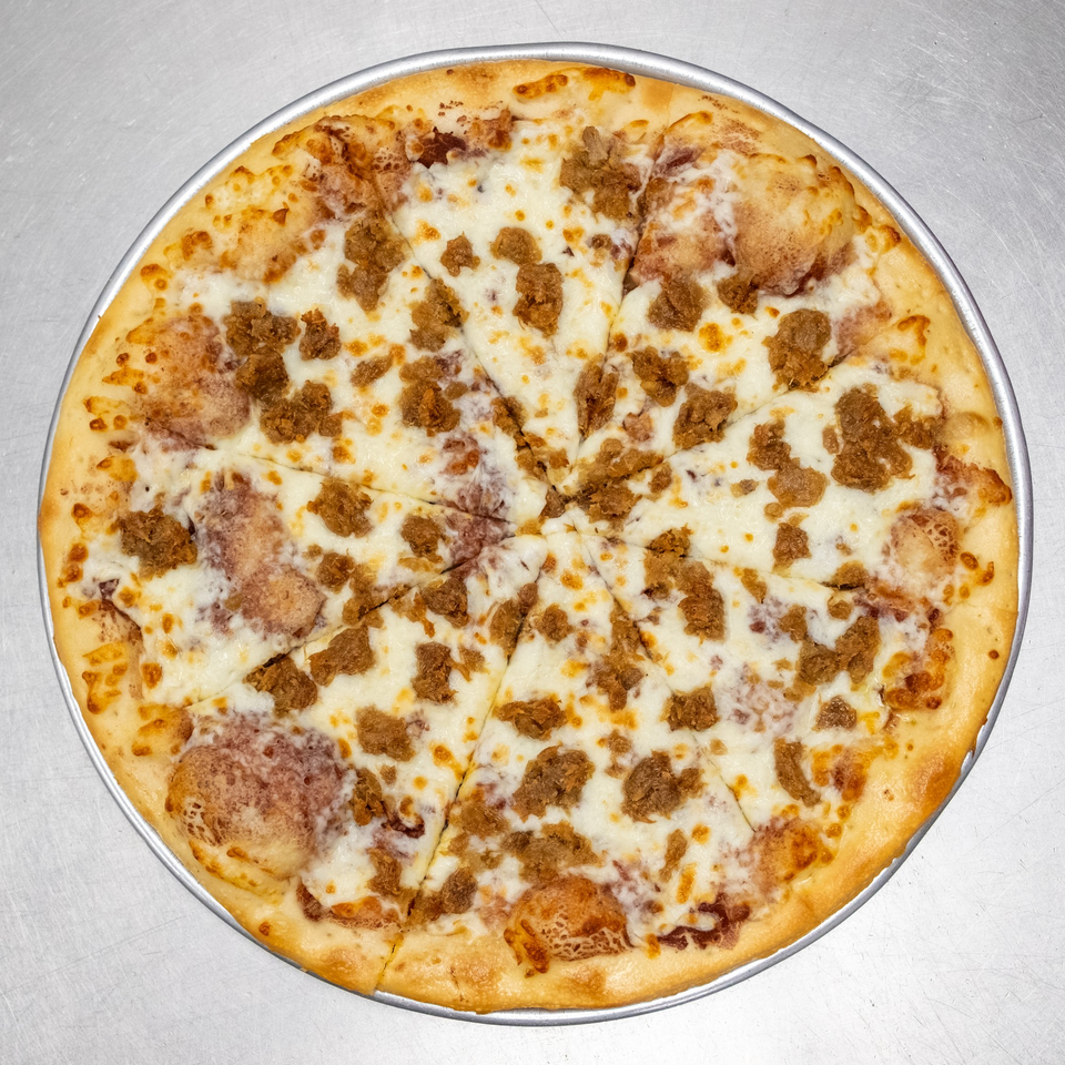 A whole, sliced pizza with white cheese and crumbled sausage on a metal tray.