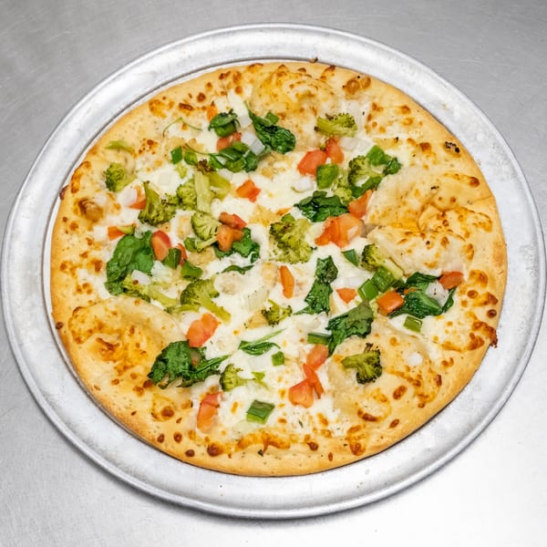 A white pizza with broccoli, spinach, tomatoes, and onions on a metal tray.
